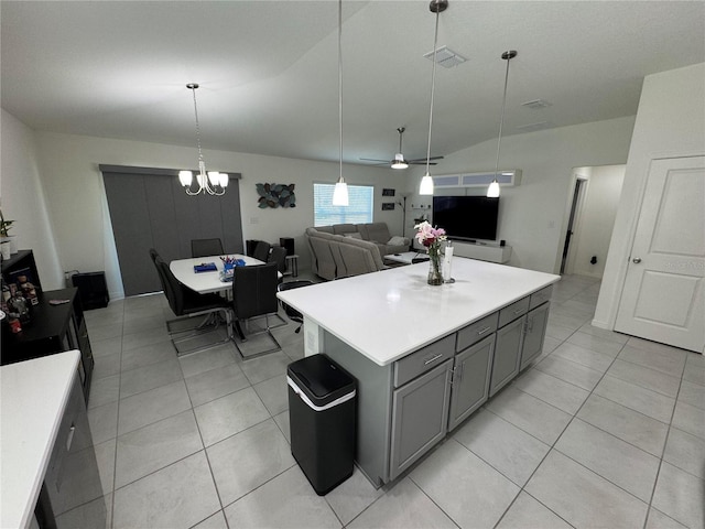 kitchen featuring light tile patterned floors, a kitchen island, gray cabinets, light countertops, and ceiling fan with notable chandelier