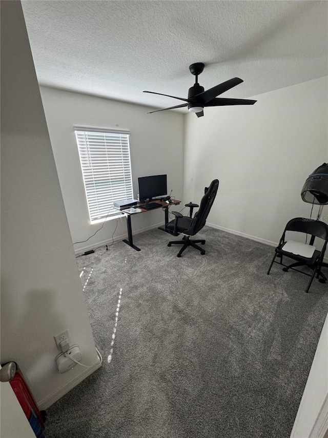 unfurnished office featuring a textured ceiling, ceiling fan, carpet flooring, and baseboards