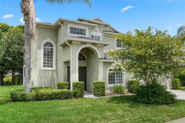 mediterranean / spanish home with a front lawn, driveway, and stucco siding