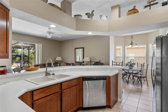 kitchen with light tile patterned floors, a sink, stainless steel appliances, light countertops, and pendant lighting