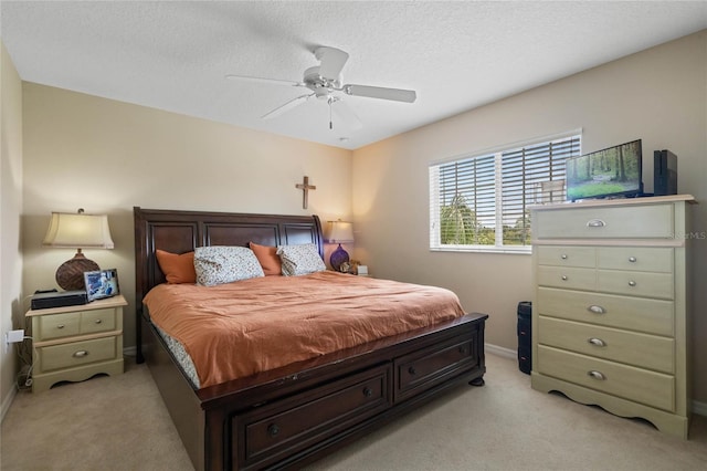 bedroom with baseboards, light carpet, a textured ceiling, and a ceiling fan