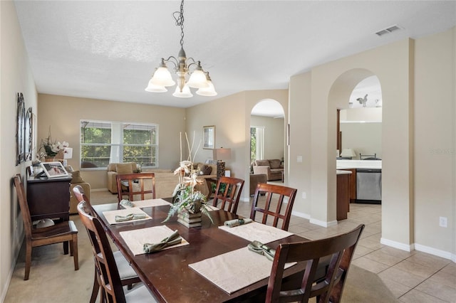 dining space featuring visible vents, light tile patterned floors, arched walkways, a notable chandelier, and a textured ceiling