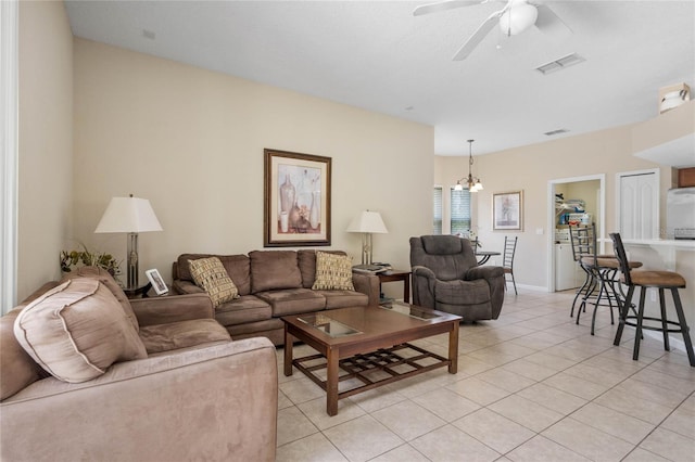 living room featuring light tile patterned flooring, ceiling fan with notable chandelier, and visible vents