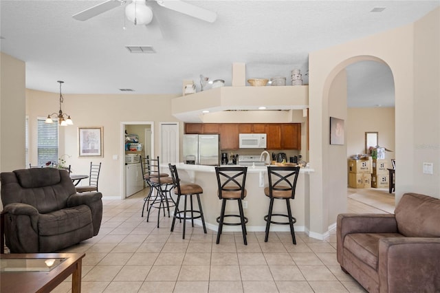 kitchen featuring white microwave, a peninsula, open floor plan, and stainless steel refrigerator with ice dispenser