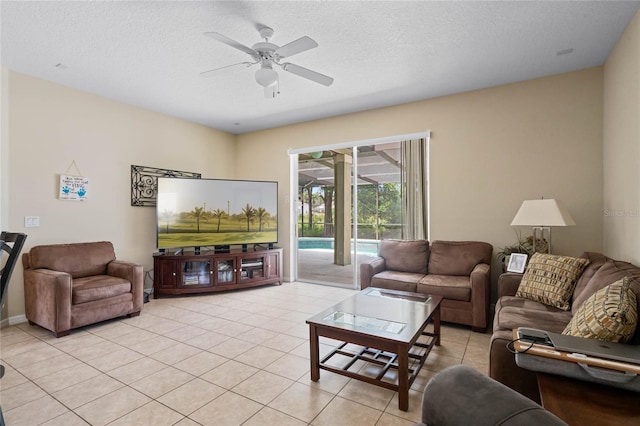 living area featuring light tile patterned floors, a ceiling fan, and a textured ceiling