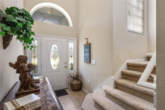 entryway featuring light tile patterned floors, baseboards, and stairs