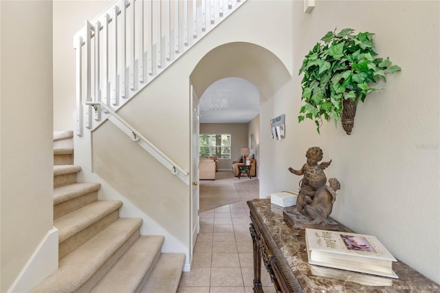 stairway featuring tile patterned floors and arched walkways