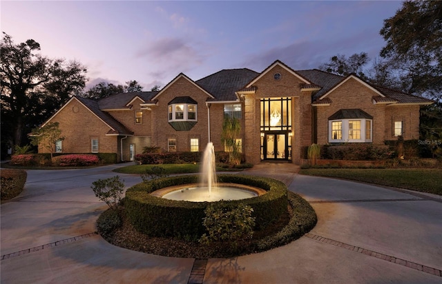 view of front of home with brick siding and curved driveway