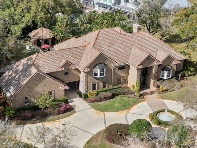 view of front facade featuring a gazebo, a tile roof, brick siding, and a chimney