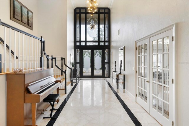 entrance foyer featuring ornamental molding, french doors, baseboards, a chandelier, and stairs