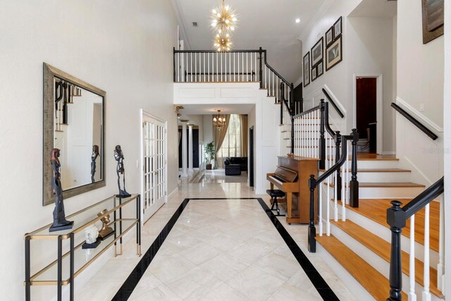 entrance foyer with stairway, baseboards, a notable chandelier, and ornamental molding