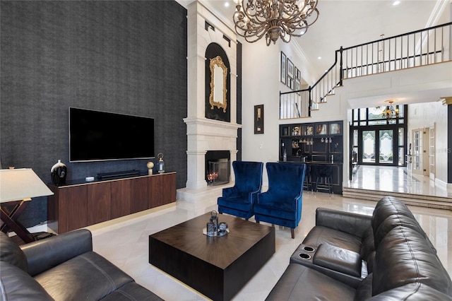 living room featuring ornamental molding, a towering ceiling, an accent wall, a notable chandelier, and a large fireplace