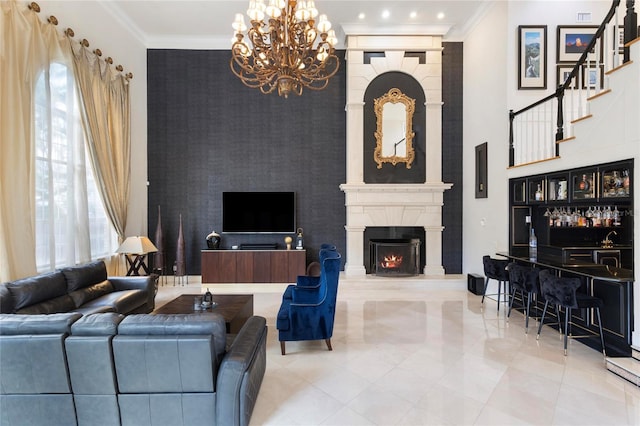 living room featuring an accent wall, a large fireplace, ornamental molding, wet bar, and an inviting chandelier