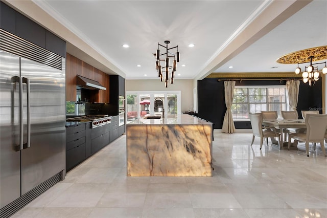 kitchen featuring under cabinet range hood, ornamental molding, a notable chandelier, stainless steel appliances, and modern cabinets