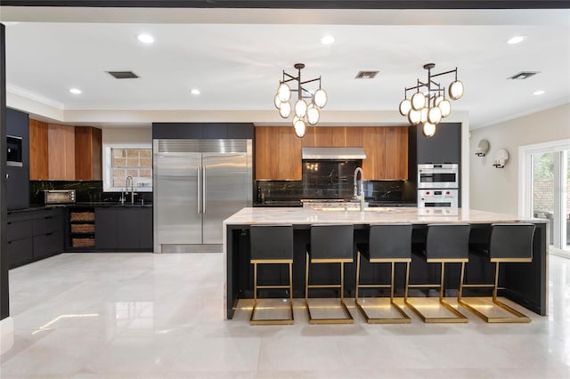 kitchen with visible vents, extractor fan, appliances with stainless steel finishes, modern cabinets, and brown cabinets