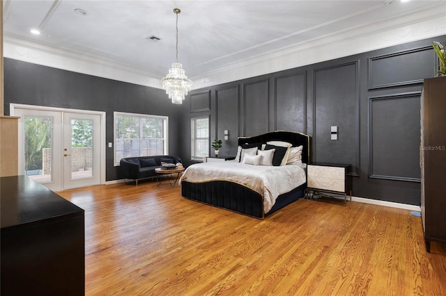 bedroom with light wood-type flooring, french doors, crown molding, a decorative wall, and access to exterior