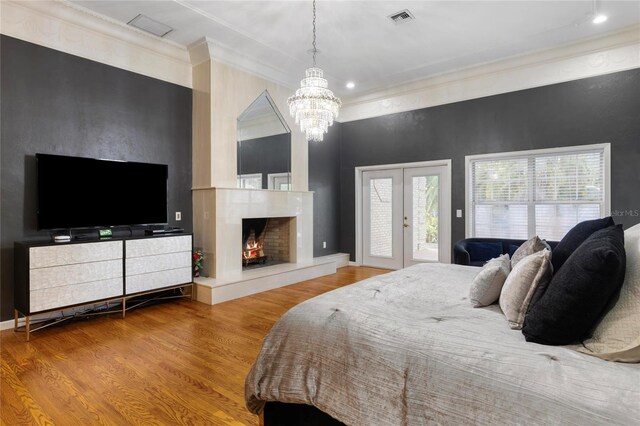 bedroom with a high end fireplace, visible vents, crown molding, wood finished floors, and access to outside