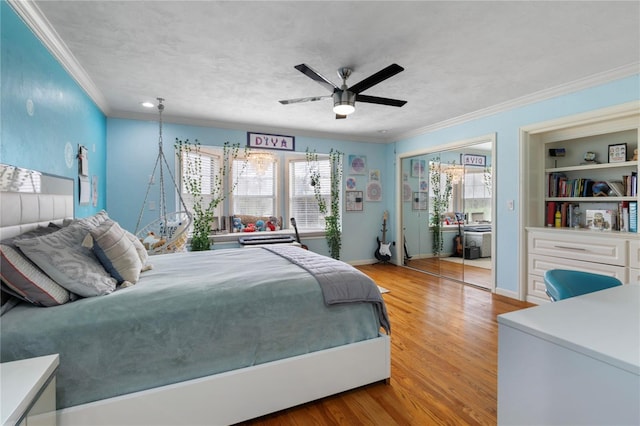 bedroom featuring a ceiling fan, wood finished floors, a closet, crown molding, and baseboards