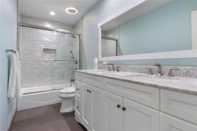 bathroom with a sink, enclosed tub / shower combo, toilet, and double vanity