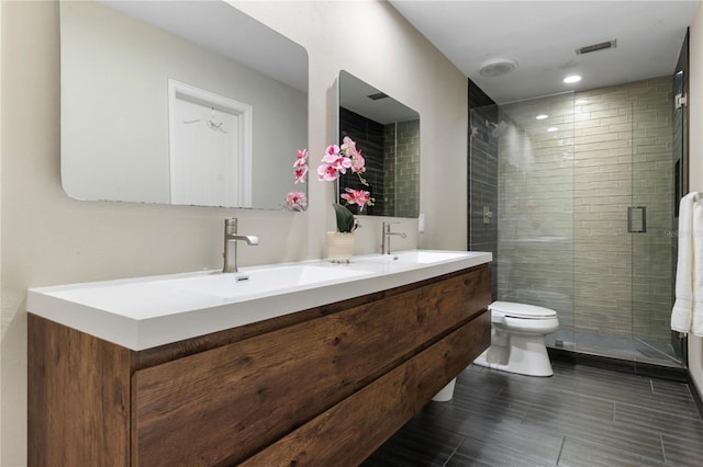 full bathroom featuring double vanity, a shower stall, toilet, and a sink