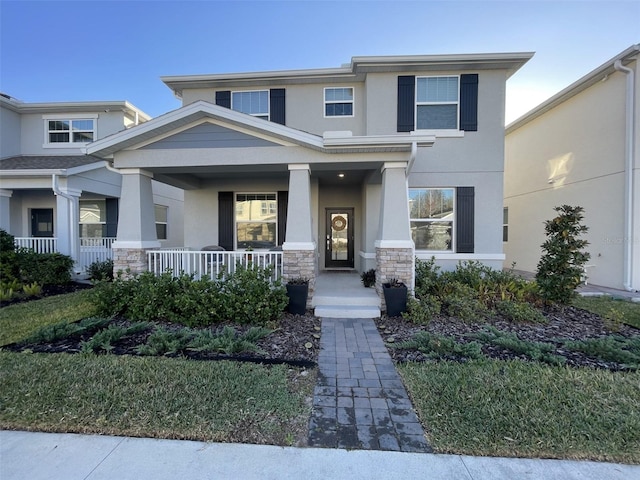 view of front of property with stucco siding, stone siding, and covered porch