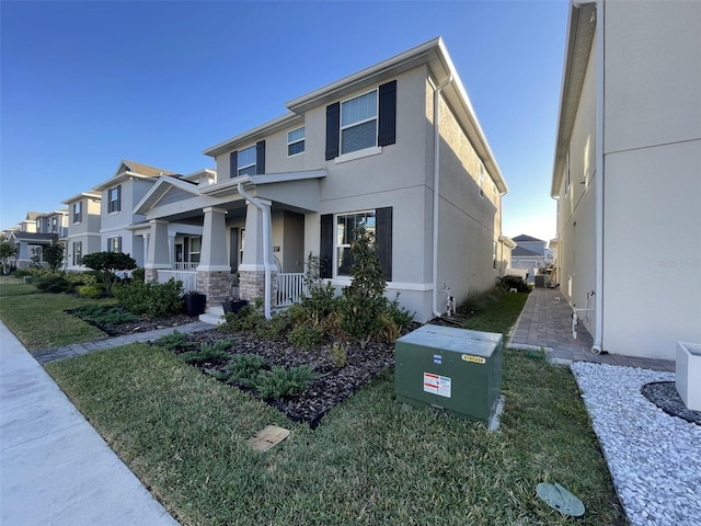 view of front of house featuring a front yard, stone siding, a residential view, and stucco siding