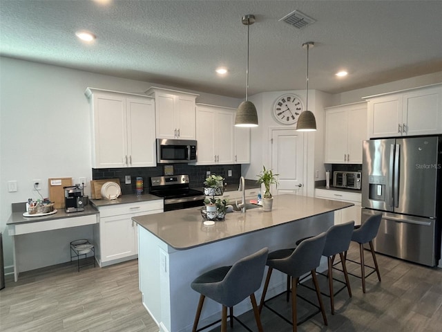 kitchen featuring light wood finished floors, tasteful backsplash, visible vents, and appliances with stainless steel finishes