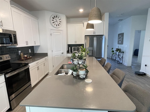 kitchen with a kitchen breakfast bar, backsplash, a spacious island, white cabinetry, and appliances with stainless steel finishes