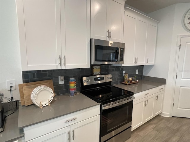 kitchen with wood finished floors, tasteful backsplash, appliances with stainless steel finishes, and white cabinets