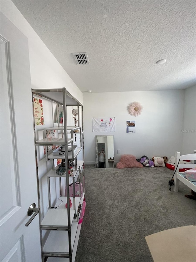 carpeted bedroom featuring visible vents and a textured ceiling