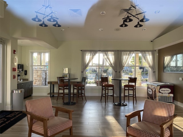 dining area featuring visible vents, baseboards, lofted ceiling, and wood finished floors