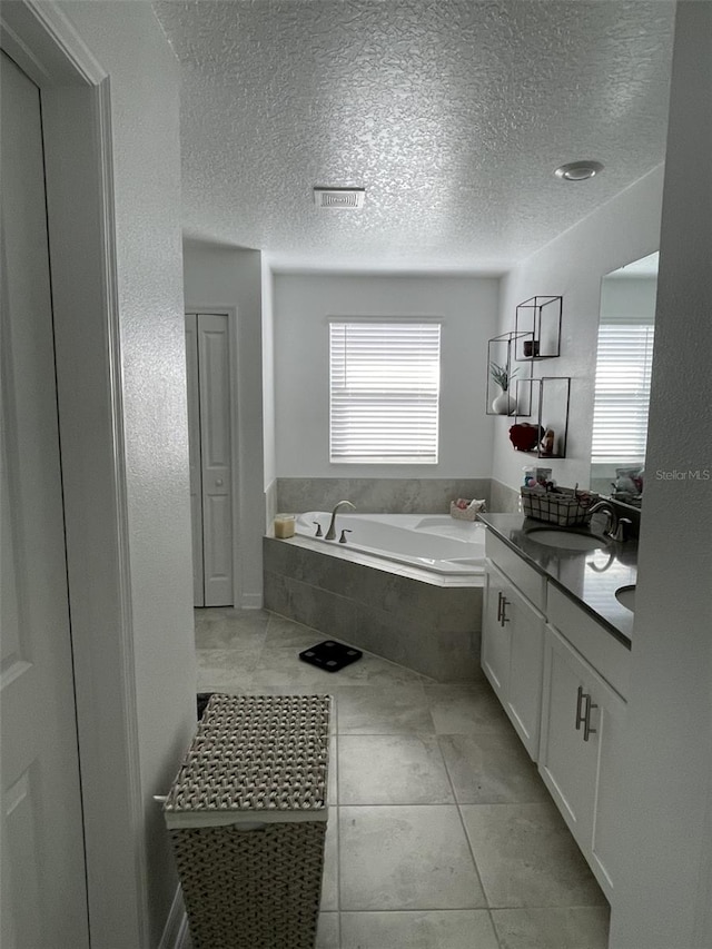 full bathroom featuring vanity, a bath, a healthy amount of sunlight, and a textured ceiling