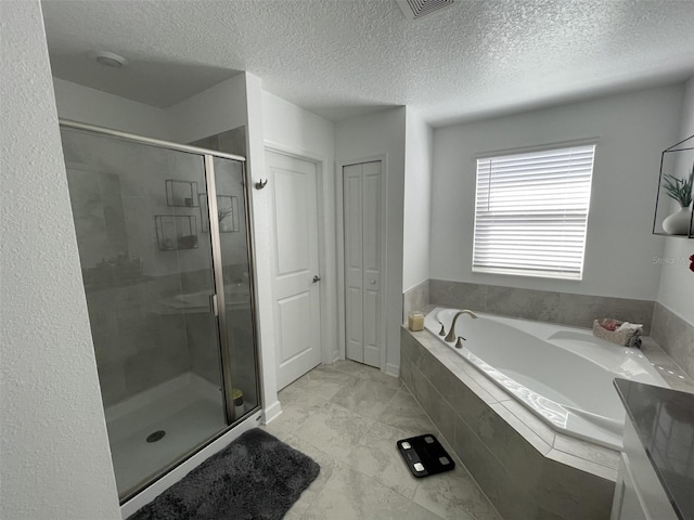 bathroom featuring a garden tub, a shower stall, and a textured ceiling