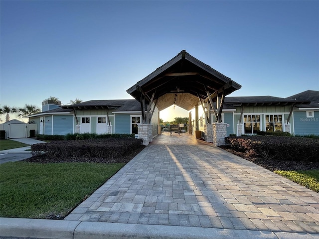 view of front facade featuring board and batten siding, decorative driveway, and a gate