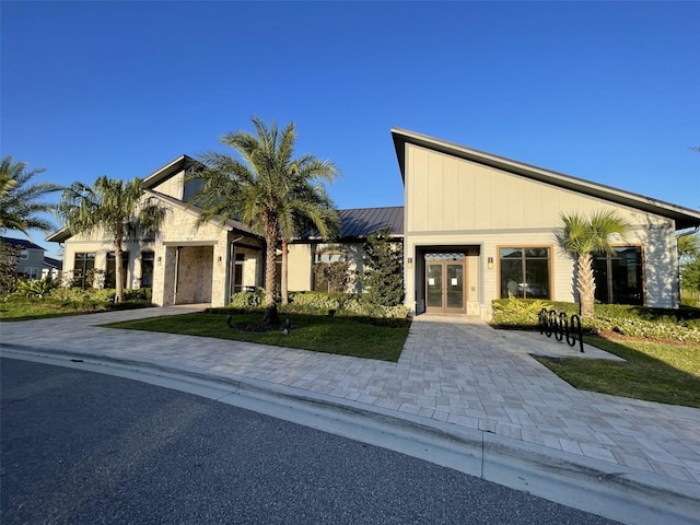 view of front of house with metal roof, a front yard, a standing seam roof, and french doors