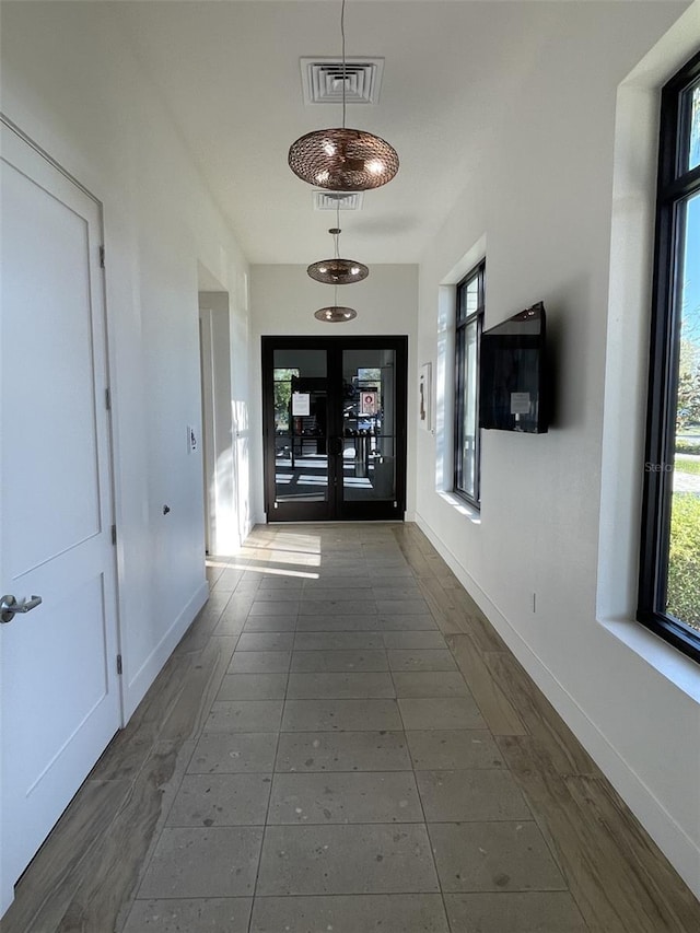 hall with dark tile patterned flooring, french doors, visible vents, and baseboards