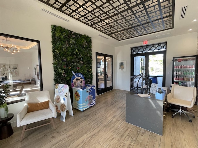 interior space featuring french doors, a raised ceiling, visible vents, and wood finished floors