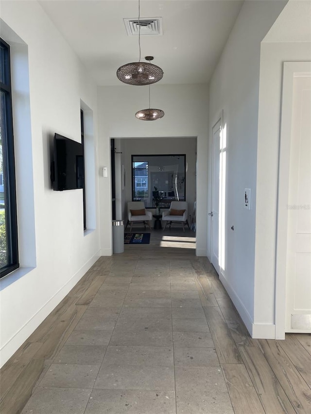 hall featuring visible vents, baseboards, and wood finished floors