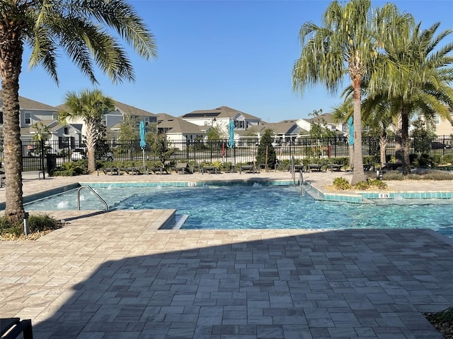 community pool with a residential view, a patio, and fence