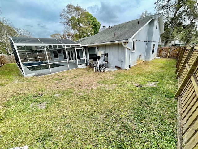 back of house with a patio area, glass enclosure, a fenced backyard, and a lawn