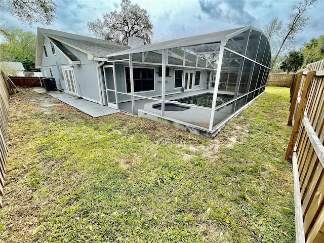 rear view of property featuring glass enclosure, a yard, a chimney, and a fenced backyard