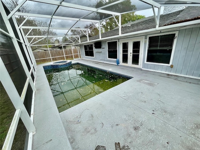 view of pool with french doors, a pool with connected hot tub, a patio area, fence, and a lanai