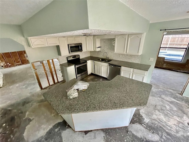 kitchen featuring lofted ceiling, a textured ceiling, stainless steel appliances, a sink, and dark countertops