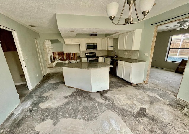 kitchen featuring stainless steel appliances, dark countertops, visible vents, white cabinetry, and a sink