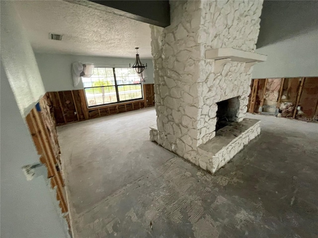 unfurnished living room featuring a notable chandelier, a fireplace, visible vents, and a textured ceiling