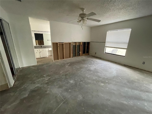 interior space with a sink, a textured ceiling, and unfinished concrete floors