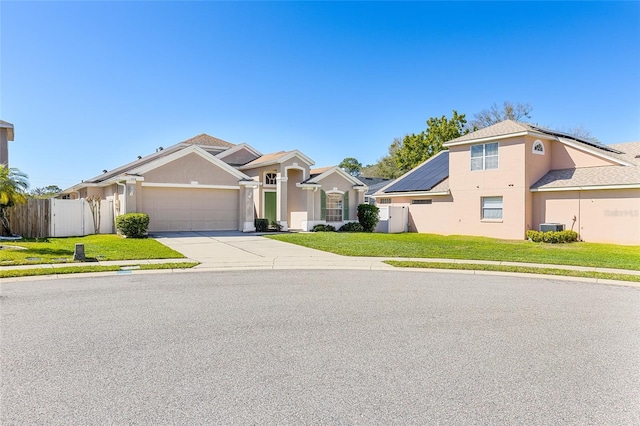 view of front of home with fence, driveway, a front lawn, and stucco siding