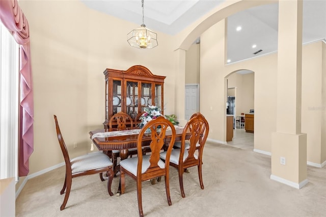 dining room with arched walkways, light carpet, baseboards, and an inviting chandelier