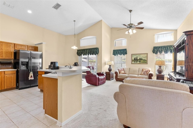 kitchen with open floor plan, a wealth of natural light, stainless steel refrigerator with ice dispenser, and visible vents