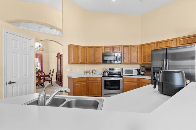 kitchen featuring stainless steel appliances, high vaulted ceiling, a sink, and light countertops